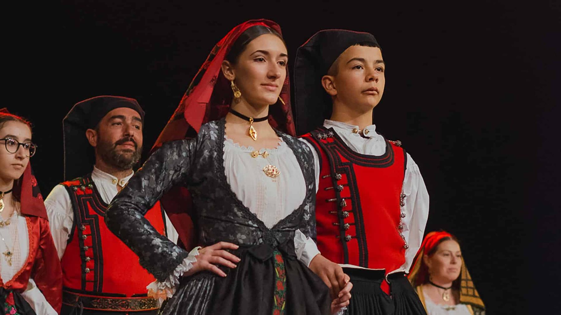 Giovani e adulti in costume tradizionale sardo durante una sfilata folkloristica in Ogliastra